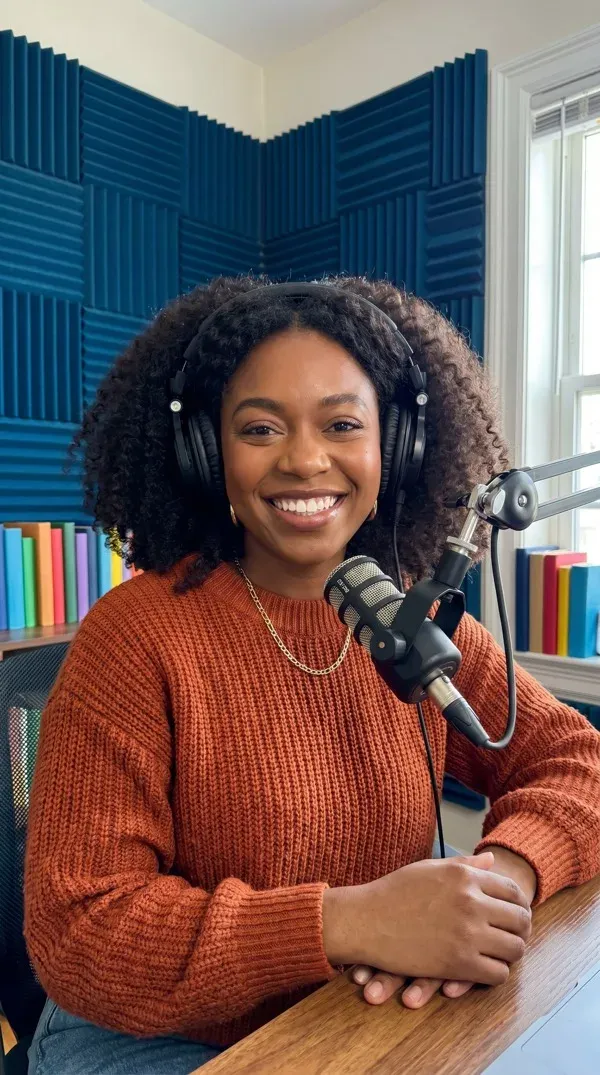 AI avatar wearing headphones at a podcast microphone in a sound-treated studio