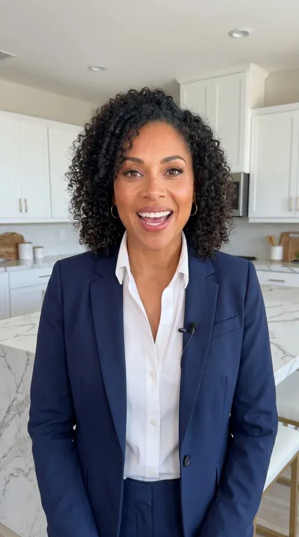AI avatar in a navy suit speaking to camera in a bright white kitchen